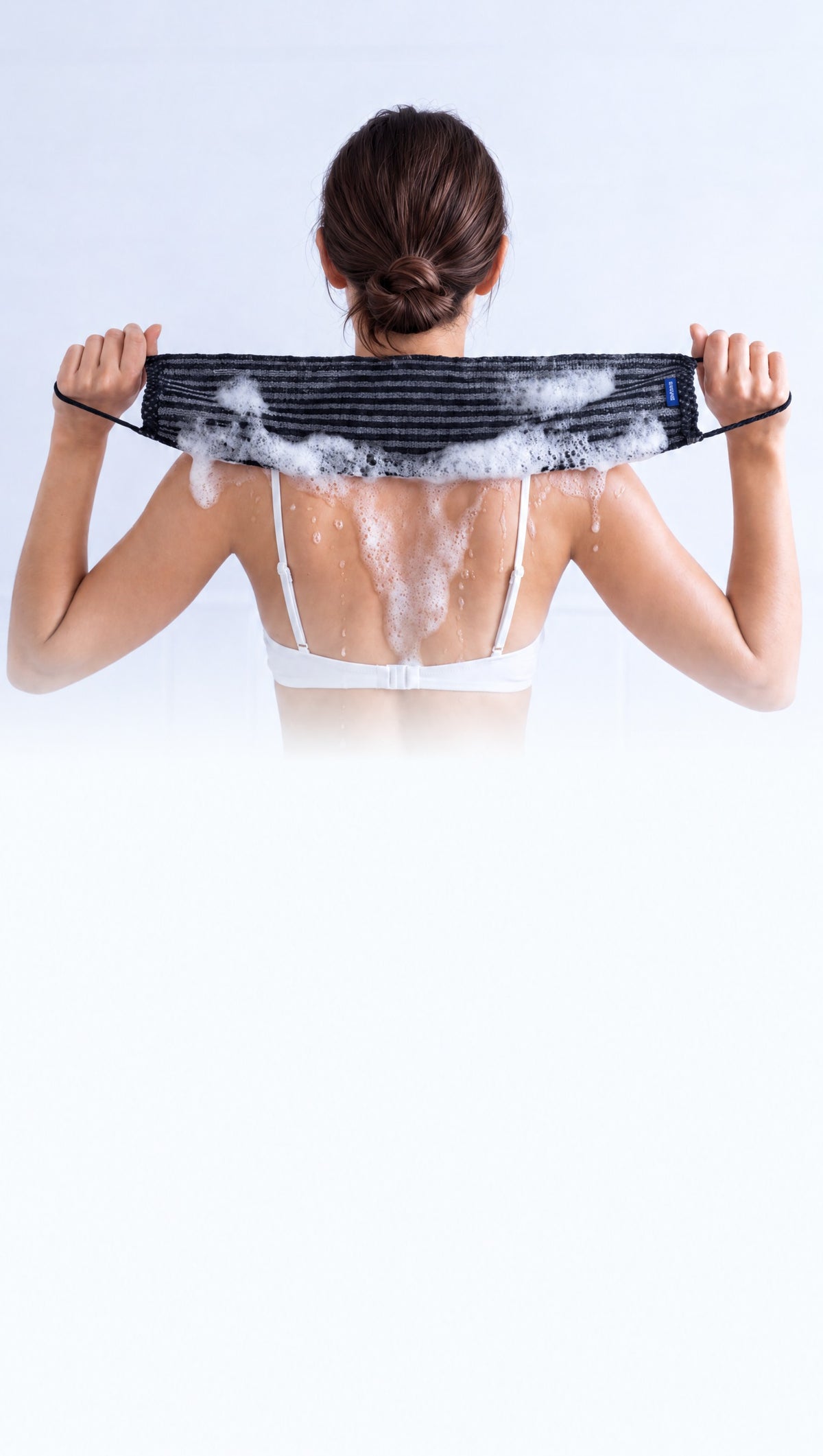 Femme utilisant la serviette exfoliante NORYA sur le dos